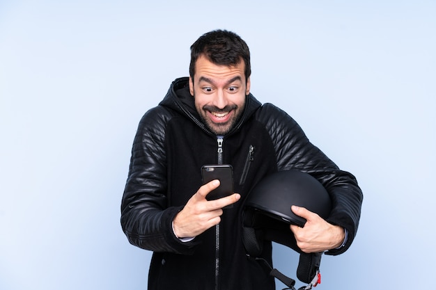 Homme avec un casque de moto sur un mur isolé surpris et envoyant un message