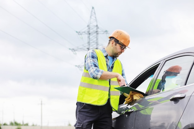 Un homme en casque et uniforme, un électricien sur le terrain. Un ingénieur électricien professionnel inspecte les lignes électriques pendant le travail.