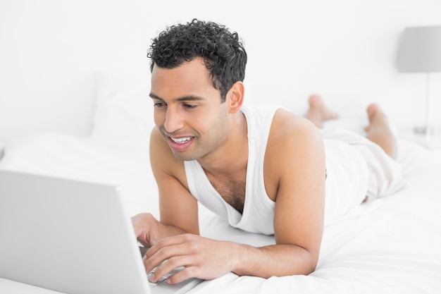 Homme Casual utilisant un ordinateur portable dans son lit