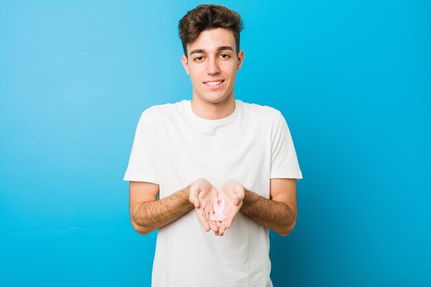 Homme caucasien adolescent avec un arc rose. Concept de lutte contre le cancer.