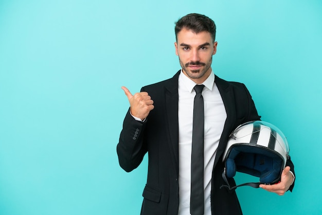 Homme caucasien d'affaires avec casque de moto isolé sur fond bleu pointant vers le côté pour présenter un produit