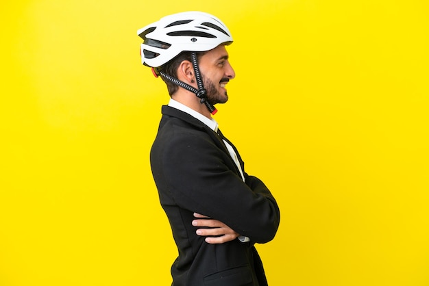 Homme caucasien d'affaires avec un casque de vélo isolé sur fond jaune en position latérale