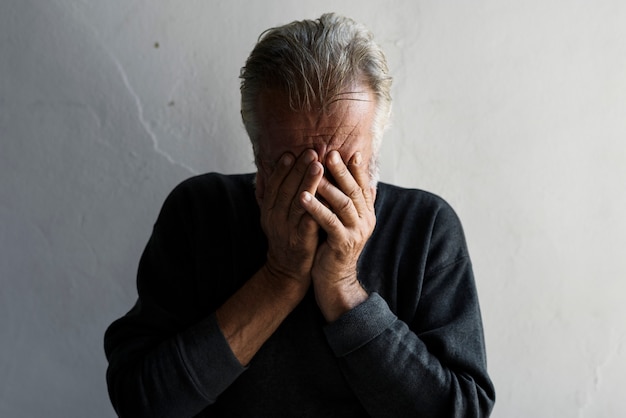 Homme caucasien âgé couvrant son visage