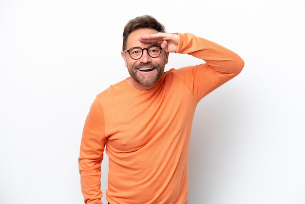 Homme caucasien d'âge moyen isolé sur fond blanc regardant loin avec la main pour regarder quelque chose