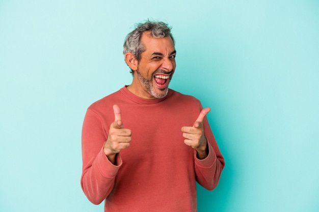 Homme caucasien d'âge moyen isolé sur fond bleu sourires joyeux pointant vers l'avant.