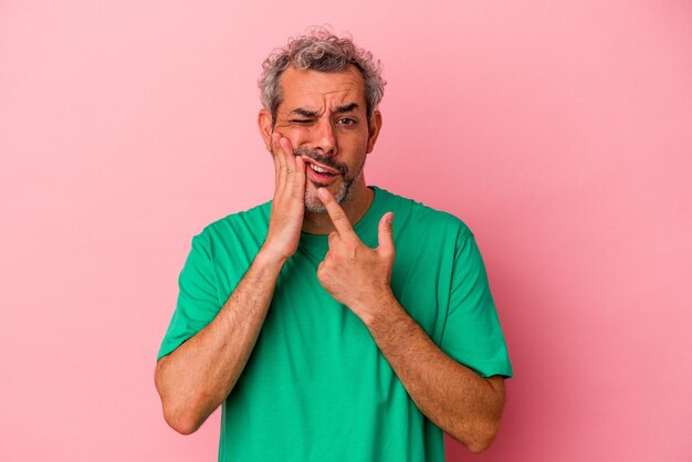 Photo homme caucasien d'âge moyen isolé sur fond rose ayant une forte douleur dentaire, une douleur molaire.