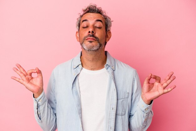 Photo un homme caucasien d'âge moyen isolé sur fond rose se détend après une dure journée de travail, elle pratique le yoga.