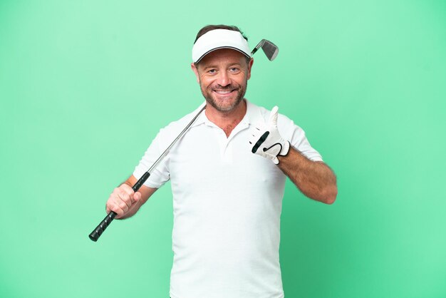 Photo homme caucasien d'âge moyen isolé sur fond vert jouant au golf et avec les pouces vers le haut parce que quelque chose de bien s'est produit