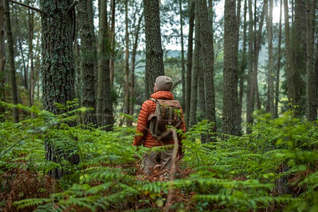 Un homme caucasien d'âge moyen avec un sac à dos face à la forêt