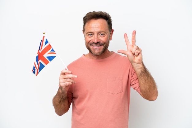 Homme caucasien d'âge moyen tenant le drapeau anglais isolé sur fond blanc heureux et comptant trois avec les doigts