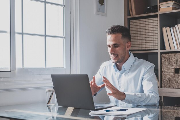 Homme caucasien attrayant assis à la maison dans une salle de bureau portant un casque participe à un webinar éducatif en utilisant un ordinateur portable Évènement d'appel vidéo avec des clients ou de conversation personnelle avec un ami à distance conceptxA