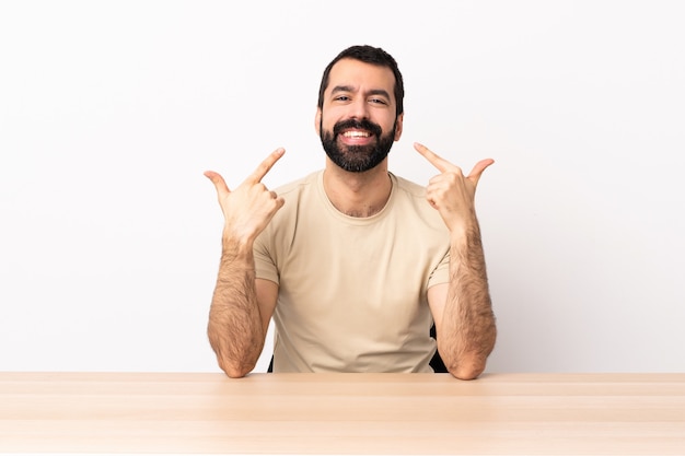 Homme caucasien avec barbe dans une table donnant un geste de pouce en l'air.