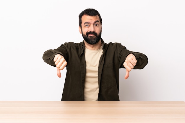 Homme caucasien, à, barbe, dans, a, table, projection, pouce bas, à, deux mains