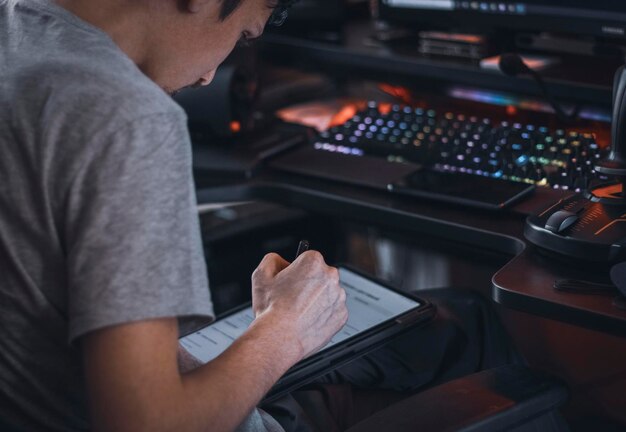 Un homme caucasien est assis sur une chaise de travail et choisit un menu en déplaçant un stylo noir sur une tablette