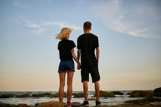 homme caucasien et fille debout embrassant au bord de la mer sur la plage au coucher du soleil