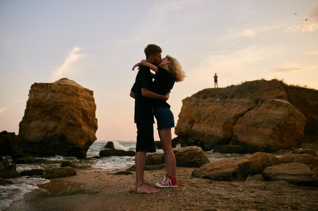 homme caucasien et fille debout embrassant au bord de la mer sur la plage au coucher du soleil