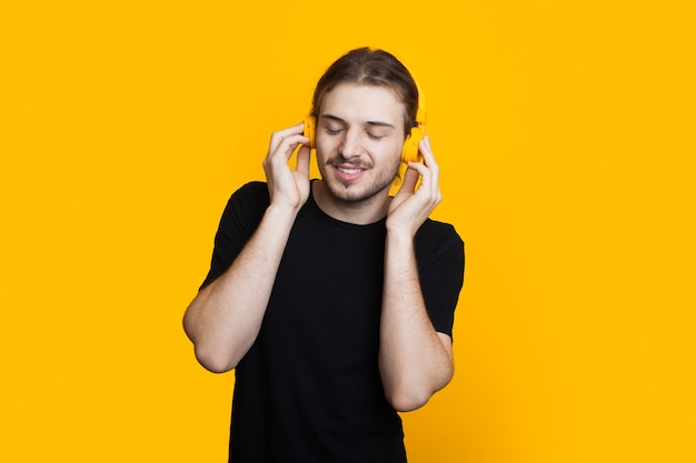 Homme caucasien mal rasé aux cheveux longs écoute de la musique à l'aide d'un casque