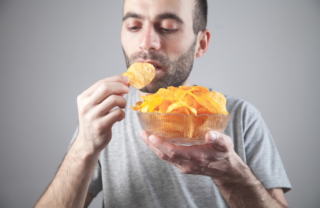 Homme caucasien, manger de savoureuses croustilles.