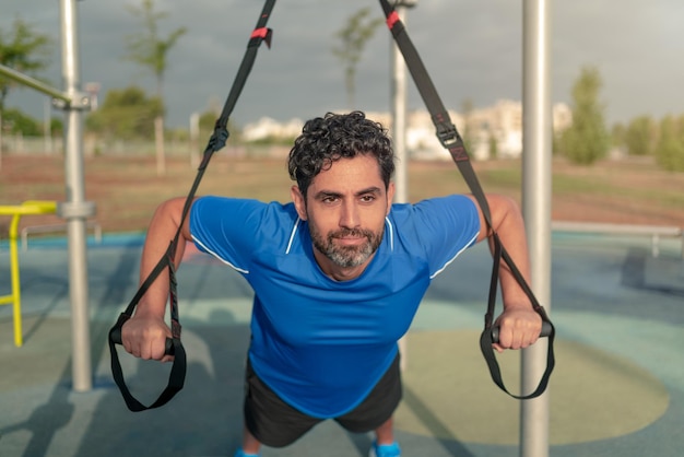 Homme caucasien pendant l'entraînement avec suspension TRX dans la rue Sangles de fitness