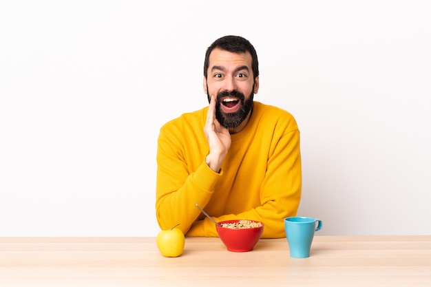 Homme caucasien prenant son petit déjeuner dans une table avec surprise et expression faciale choquée.