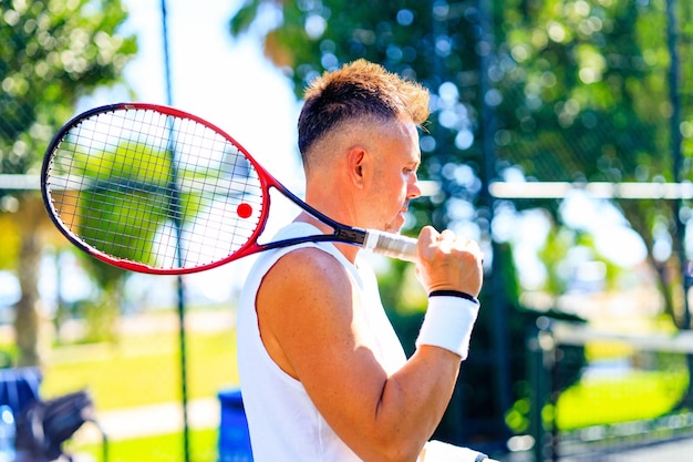 Homme caucasien senior jouant au tennis sur le court tenant une raquette de tennis lumière du jour à l'extérieur à l'air frais