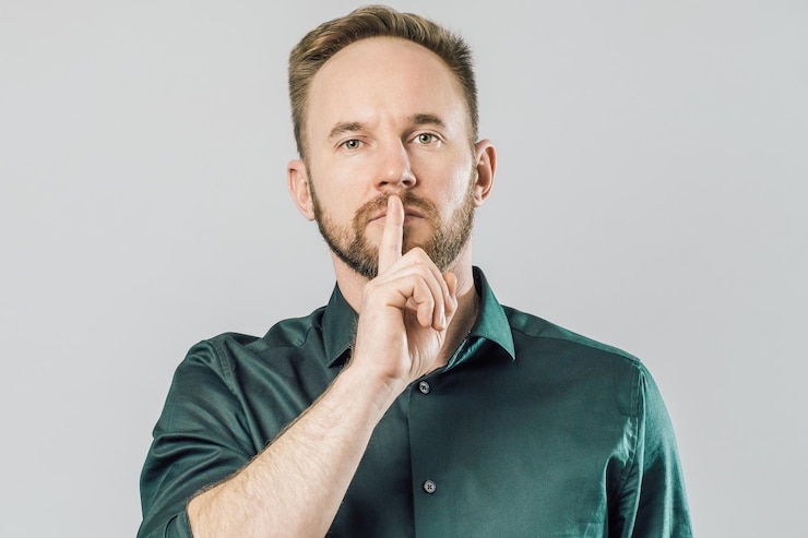 Photo un homme caucasien sérieux tenant l'index sur la bouche en disant shh sur un fond gris