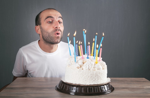 Homme caucasien soufflant des bougies d'anniversaire.