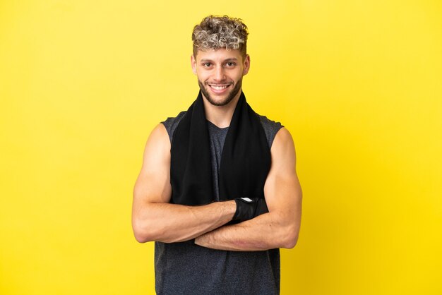 Homme caucasien sport isolé sur fond jaune en gardant les bras croisés en position frontale