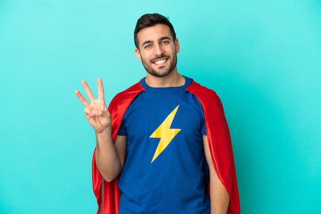 Homme caucasien de super héros isolé sur fond bleu heureux et comptant trois avec les doigts