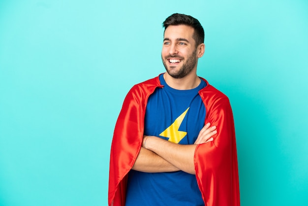 Homme caucasien de super héros isolé sur fond bleu heureux et souriant