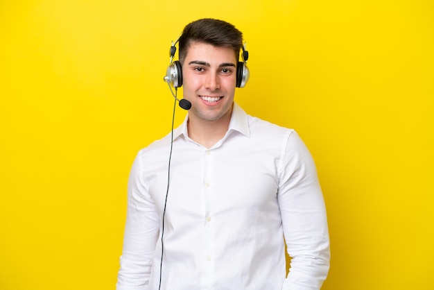 Homme caucasien de télévendeur travaillant avec un casque isolé sur fond jaune en riant