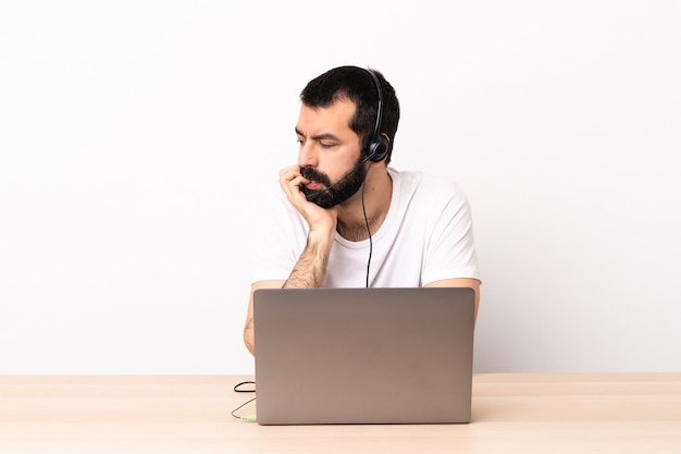 Homme caucasien de télévendeur travaillant avec un casque et avec un ordinateur portable ayant des doutes.