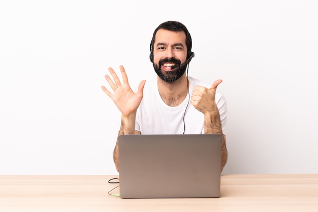 Homme caucasien de télévendeur travaillant avec un casque et avec un ordinateur portable en comptant six avec les doigts.