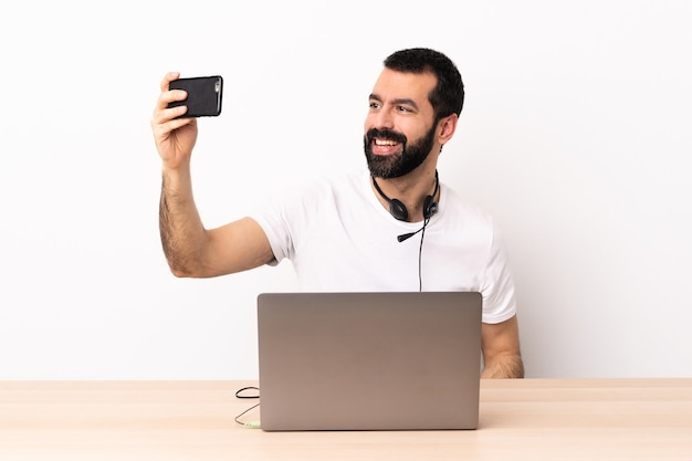 Homme caucasien de télévendeur travaillant avec un casque et avec un ordinateur portable faisant un selfie.