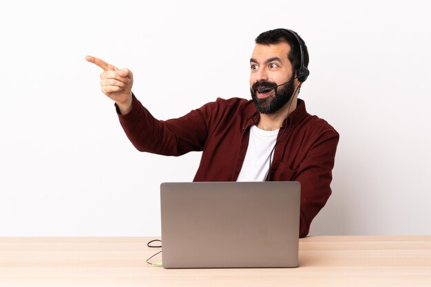 Homme caucasien de télévendeur travaillant avec un casque et avec un ordinateur portable pointant vers l'extérieur.