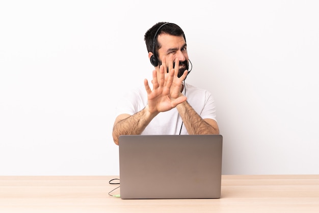 Homme caucasien de télévendeur travaillant avec un casque et avec un ordinateur portable s'étendant les mains nerveuses vers l'avant.