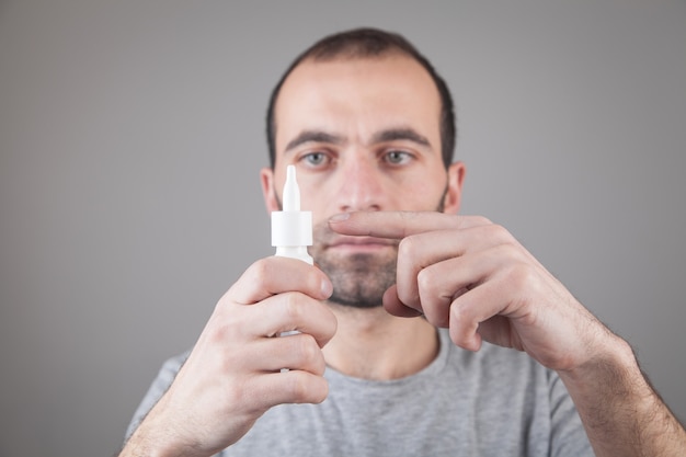 Homme caucasien tenant une bouteille de gouttes pour les yeux.