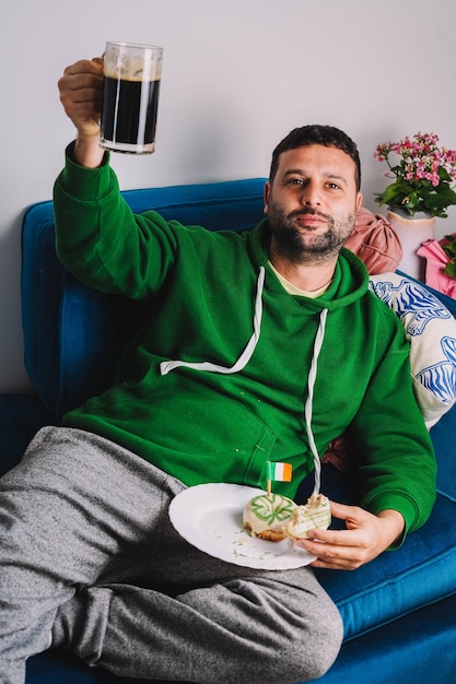 Un homme célibataire ayant des beignets et du stout pour le petit-déjeuner pour célébrer la Saint-Patrick