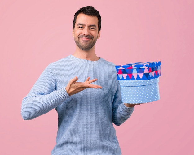 Homme avec un chandail bleu tenant des boîtes-cadeaux dans les mains