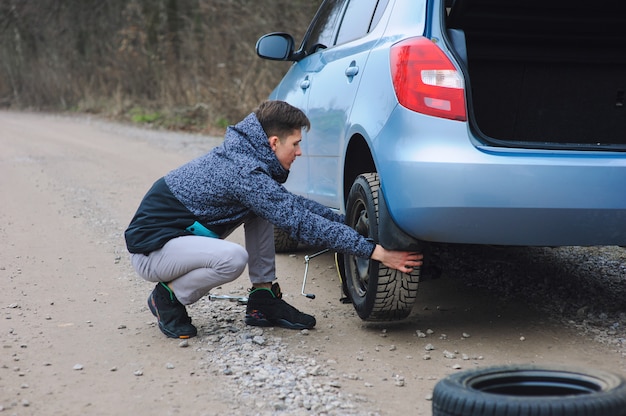 L'homme Change De Pneu Avec Roue Sur La Voiture