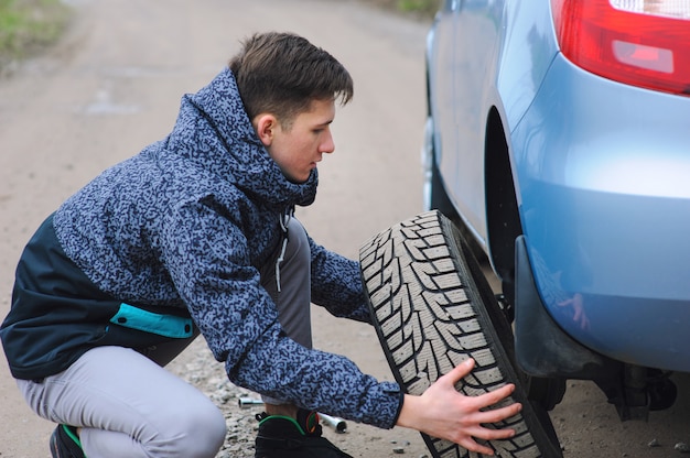 L'homme Change De Pneu Avec Roue Sur La Voiture