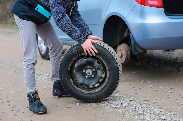 L'homme change de pneu avec roue sur la voiture