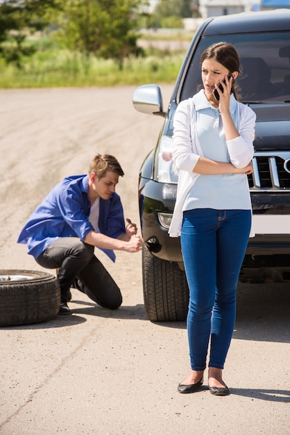 L'homme change de roue dans la voiture et la fille appelle.