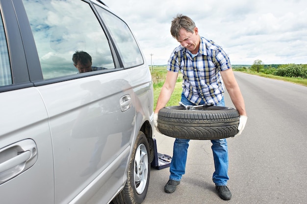 Homme changeant une roue de secours de voiture