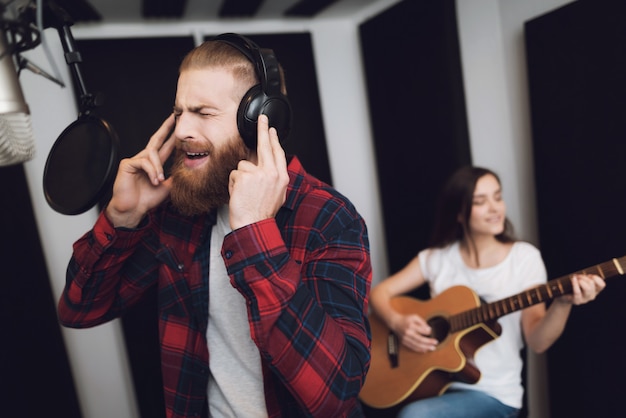 Un homme chante et une femme joue de la guitare.