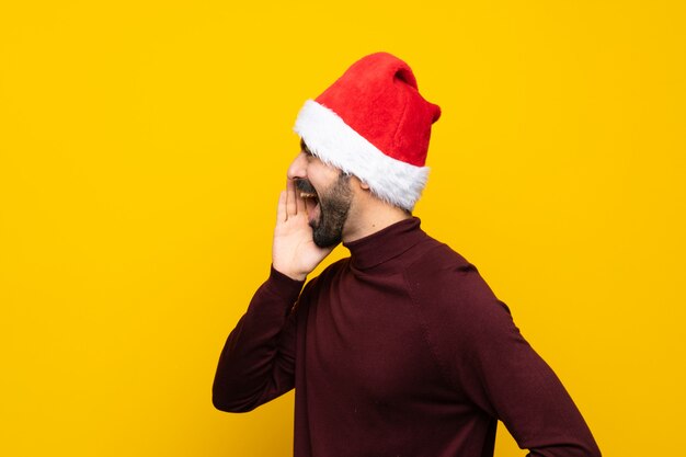 Homme avec chapeau de Noël criant sur fond jaune isolé