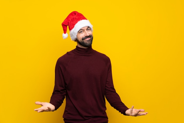 Homme avec un chapeau de Noël sur mur jaune isolé souriant