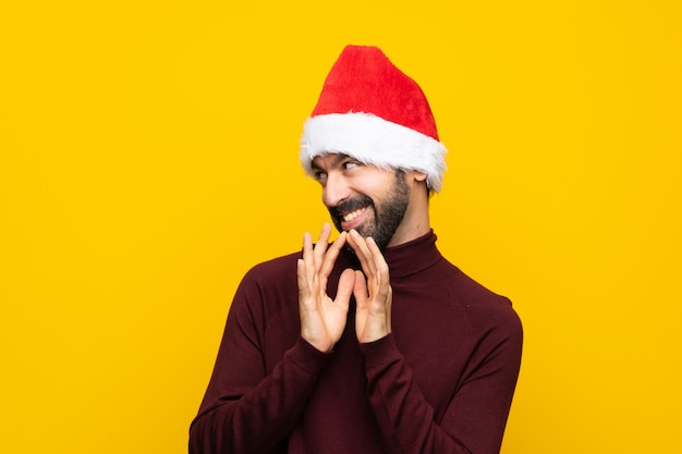 Homme avec un chapeau de Noël sur un mur jaune isolé