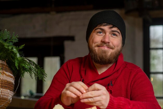 Un homme avec un chapeau et un pull mange une mandarine