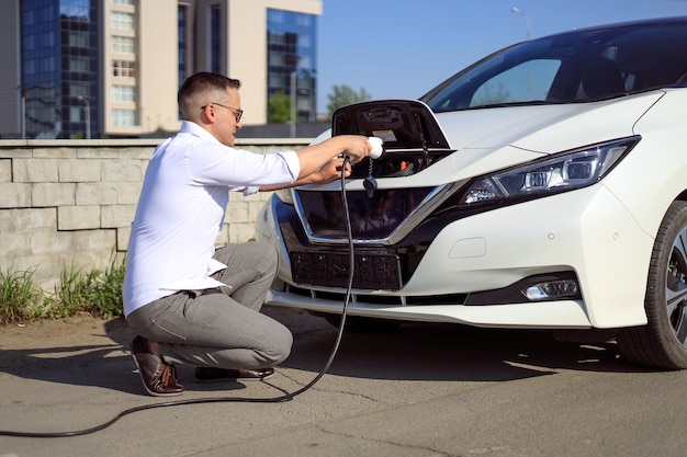 Un homme charge une voiture électrique dans un concept d'énergie verte et d'énergie écologique visant à réduire les émissions de CO2